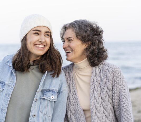 madre e hija sonrientes en un paseo por la playa