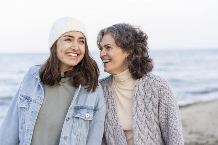 Un homenaje a las madrese en el día de la madre madre e hija sonrientes en un paseo por la playa
