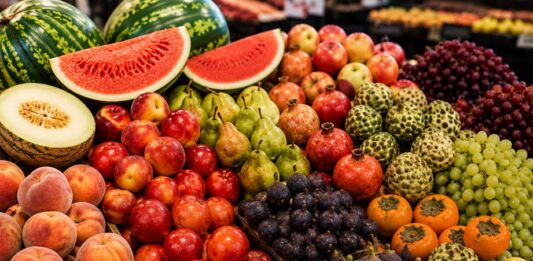 Mercaddo con estantes que muestran frutas de temporada de septieembre.