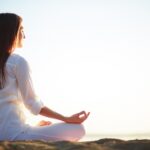 Una mujer meditando en posición de lotus al aire libre