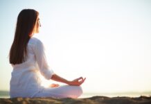 Una mujer meditando en posición de lotus al aire libre