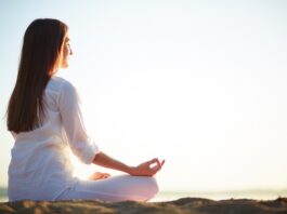 Una mujer meditando en posición de lotus al aire libre