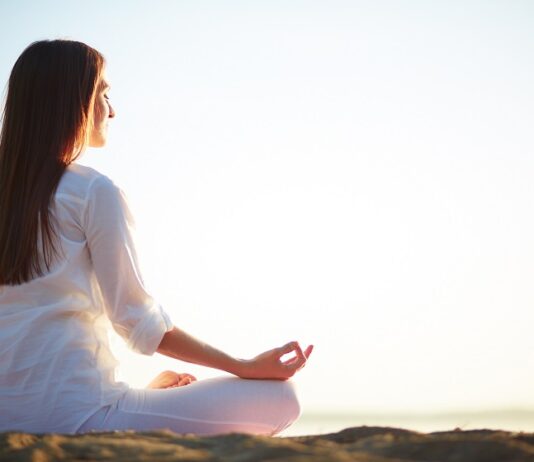 Una mujer meditando en posición de lotus al aire libre