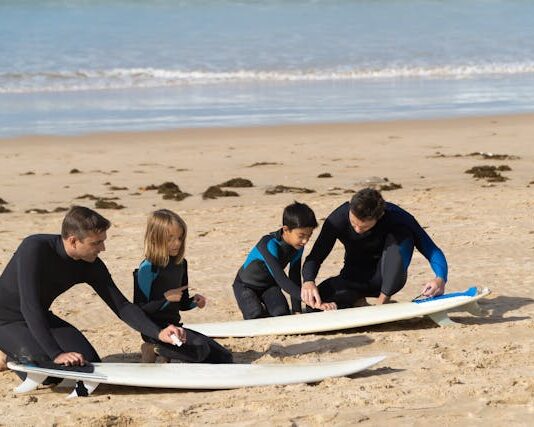 Niños con instructor en la arena, preparándose para hacer surf