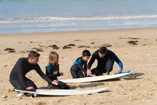 niños-preparandose-para-hacer-surf Niños con instructor en la arena, preparándose para hacer surf