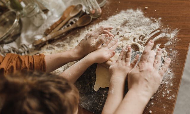 niños en la cocina ayudando a amasar la harina