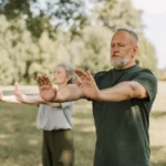 Tai Chi y diabetes: ejercicio suave para moverse mejor y cuidar la glucemia Dos personas adultas practican Tai Chi al aire libre en un parque, una actividad suave y de bajo impacto adecuada para mejorar equilibrio y movilidad.