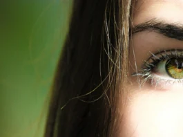 Perfil de una chica, muestra solo un ojo, el otro queda ocultado. Tiene los ojos de color verde y una melena lacia.