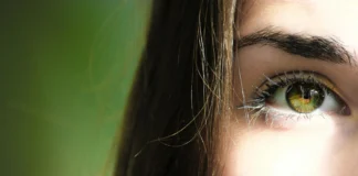 Perfil de una chica, muestra solo un ojo, el otro queda ocultado. Tiene los ojos de color verde y una melena lacia.